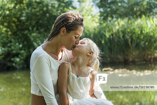 Mother and daughter kissing at a lake