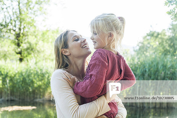 Mother holding daughter at a lake