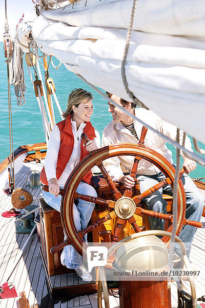 Happy mature couple at helm of a sailing ship