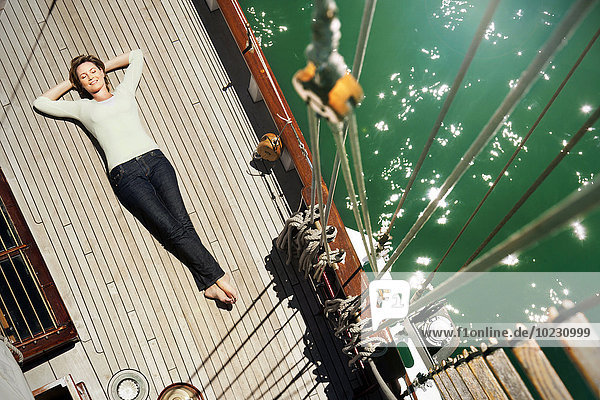 Relaxed mature woman lying on deck of a sailing ship