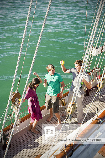 Glückliche Freunde beim Trinken und Tanzen an Deck eines Segelschiffes
