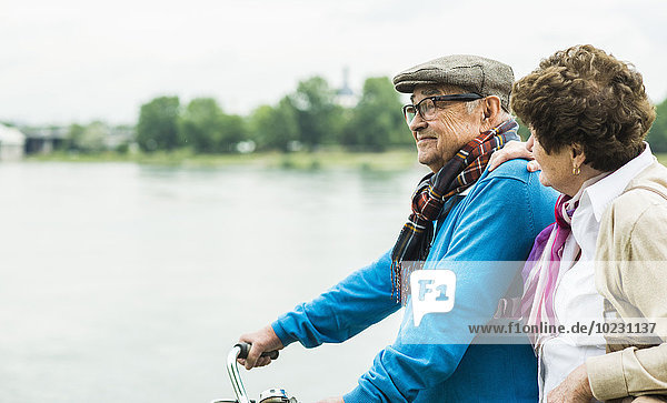 Senior couple with bicycle in front of water