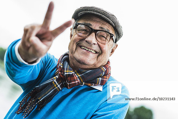 Porträt eines glücklichen älteren Mannes mit Siegeszeichen