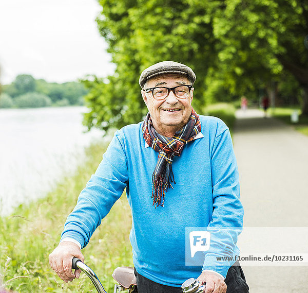 Porträt eines glücklichen älteren Mannes auf seinem Fahrrad