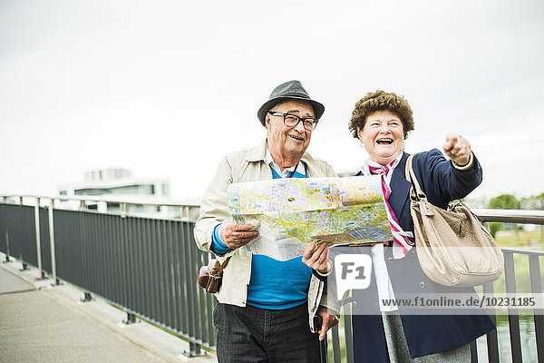 Seniorenpaar mit Karte auf einer Brücke stehend