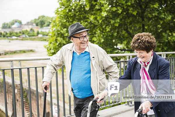 Laughing senior couple with walking stick and wheeled walker