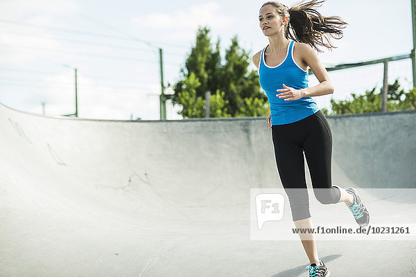 Sportliche junge Frau beim Laufen im Skatepark