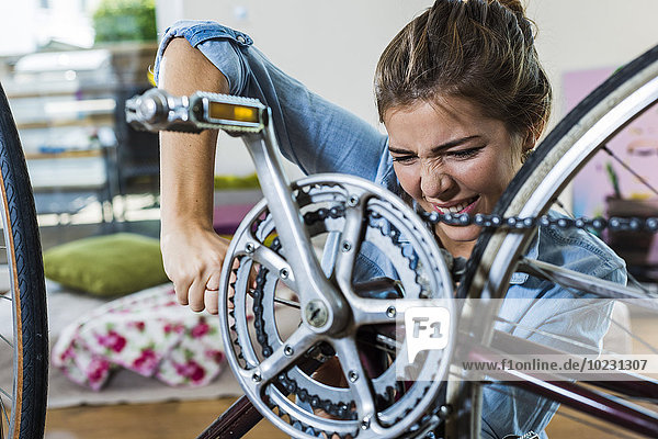 Ausgeübte junge Frau zu Hause  die ihr Fahrrad repariert.