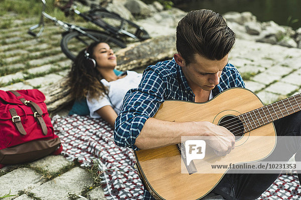 Entspanntes junges Paar mit Gitarre im Freien