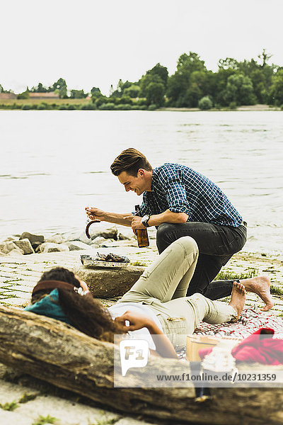 Young couple having a barbecue by the riverside