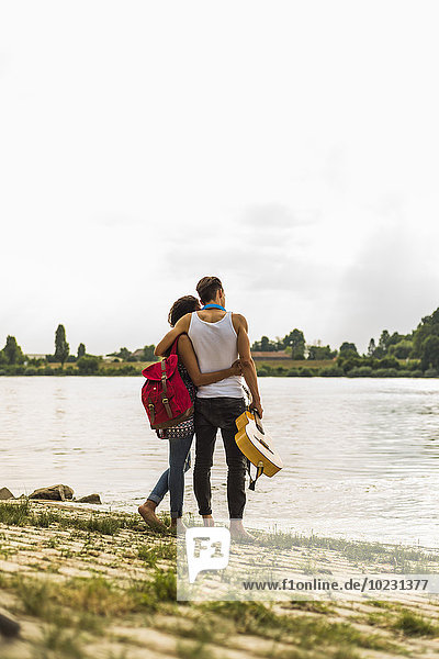 Junges Paar  das sich am Flussufer umarmt