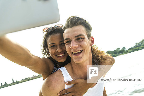 Ein glückliches junges Paar  das einen Selfie am Flussufer nimmt.