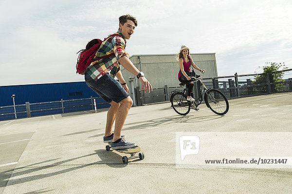 Happy young couple with bicycle and skateboard
