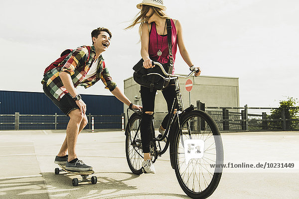 Happy young couple with bicycle and skateboard