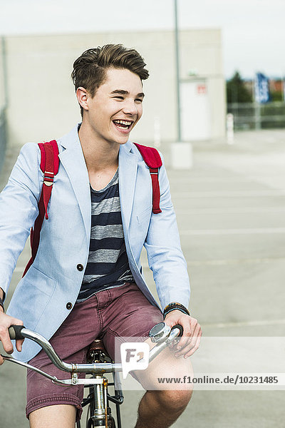 Glücklicher junger Mann beim Fahrradfahren auf der Parkebene
