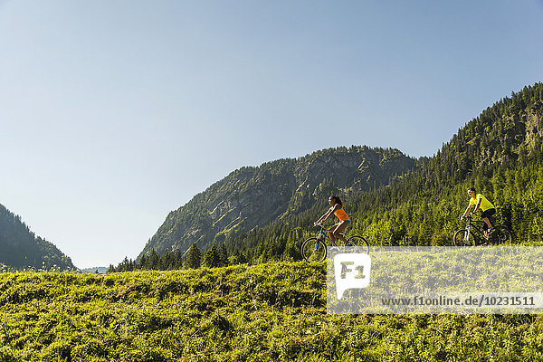 Austria  Tyrol  Tannheim Valley  young couple on mountain bikes in alpine landscape