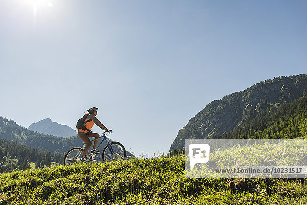 Austria  Tyrol  Tannheim Valley  young woman on mountain bike in alpine landscape