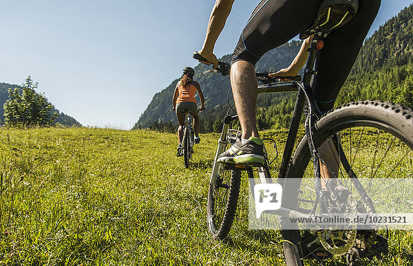 Austria  Tyrol  Tannheim Valley  young couple on mountain bikes in alpine landscape