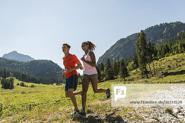 Austria  Tyrol  Tannheim Valley  young couple jogging in alpine landscape