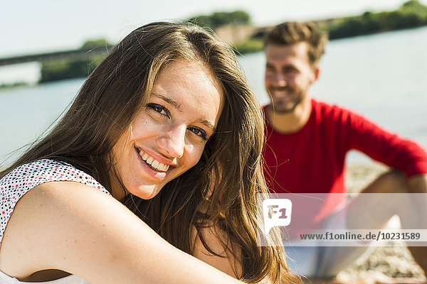 Porträt einer glücklichen jungen Frau mit Mann am Flussufer
