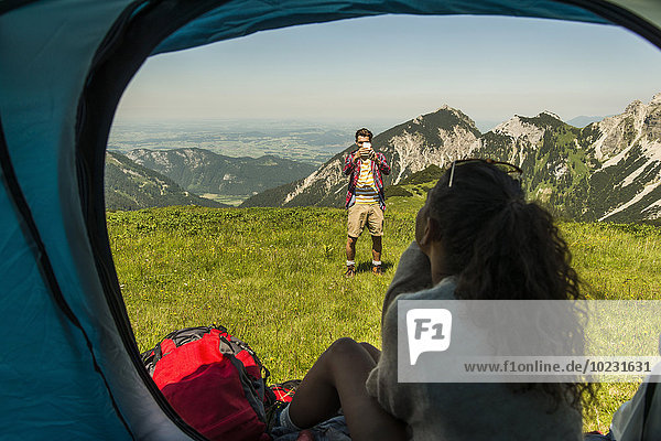 Austria  Tyrol  Tannheimer Tal  young man taking picture of woman in tent