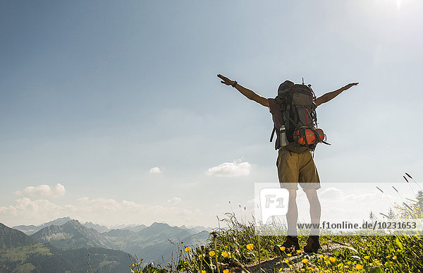 Austria  Tyrol  Tannheimer Tal  young man standing on mountain trail with arms outstretched