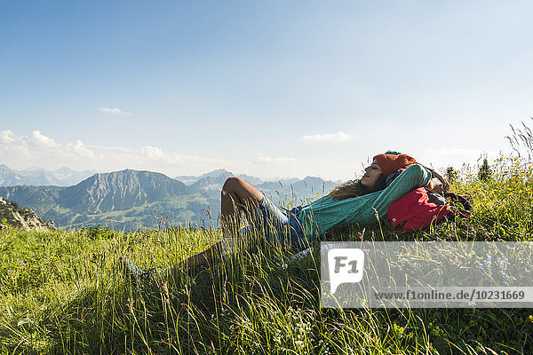 Austria  Tyrol  Tannheimer Tal  young woman lying on alpine meadow