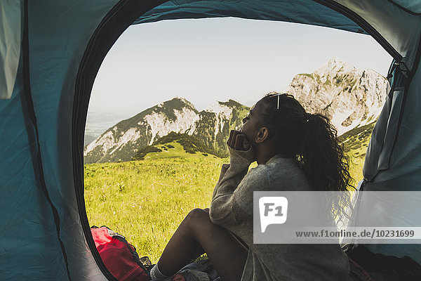 Österreich  Tirol  Tannheimer Tal  junge Frau sitzend im Zelt auf der Alm