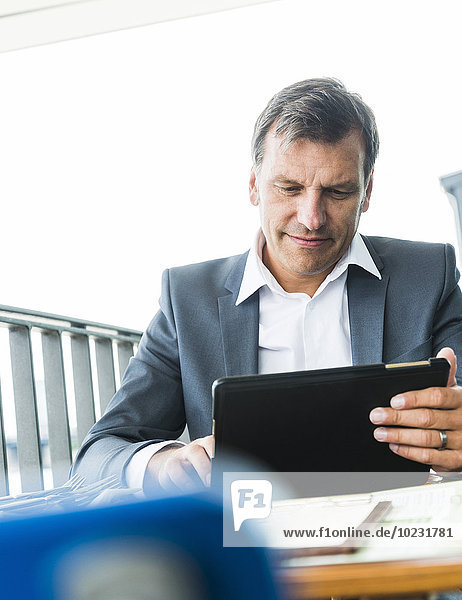 Geschäftsmann im Freien sitzend  mit digitalem Tablett