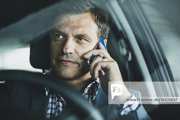 Reife Geschäftsleute mit Smartphone im Auto