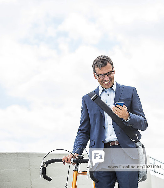 Geschäftsmann mit Fahrrad über Smartphone