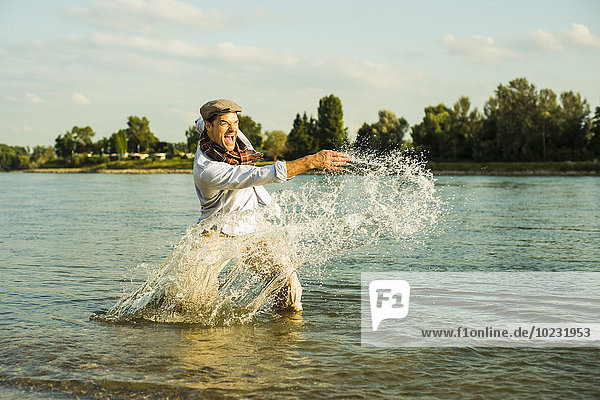 Mann steht im Fluss und spritzt vor Wasser.