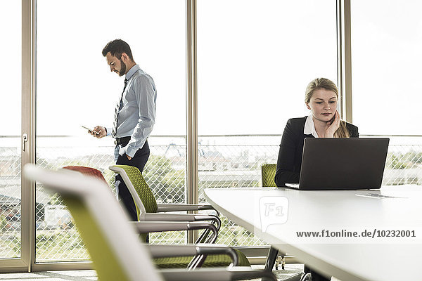 Businessman and young businesswoman in conference room with laptop