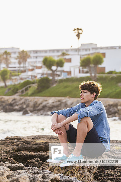 Greece  Rhodes  young man sitting at seafront looking at distance