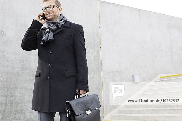 Smiling businessman outdoors on the phone