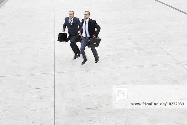 Two businessmen running outdoors