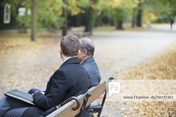 Two businessmen sitting on park bench