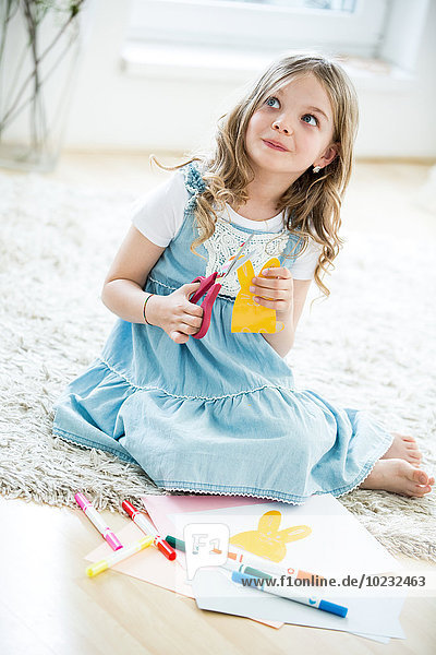 Kleines Mädchen  das Osterhasen aus Papier ausschneidet