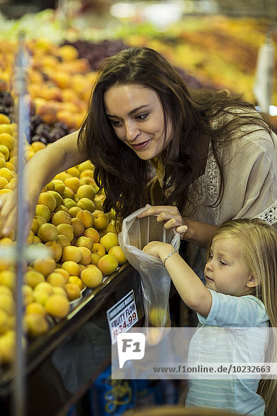 Mutter und Tochter im Supermarkt beim Pfirsich-Shopping