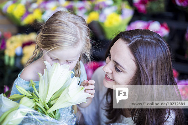 Mutter und Tochter riechende Blume im Laden