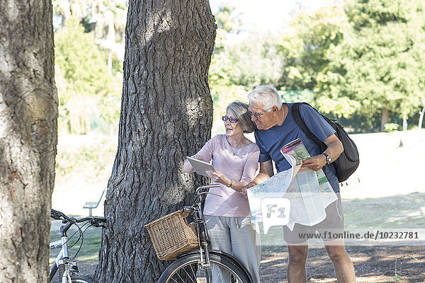 Senior couple with bicycles looking at digital tablet