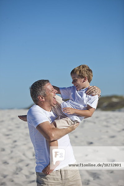 Playful father and son in sand