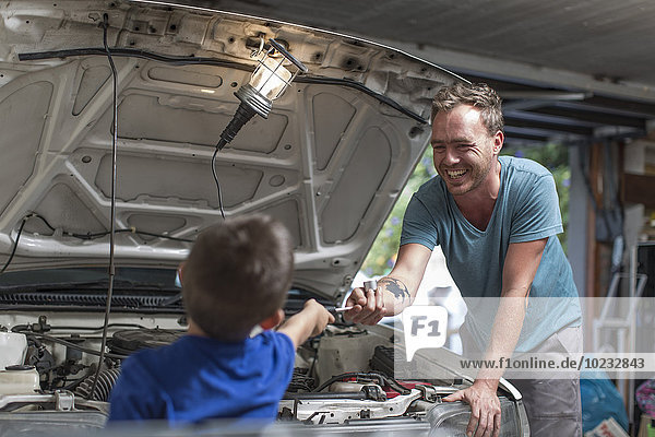 Sohn hilft Vater in der heimischen Garage bei der Arbeit am Auto