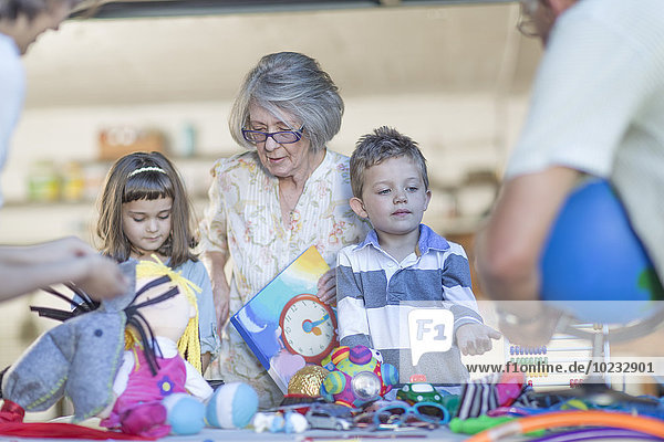 Kids having a garage sale assisted by grandmother