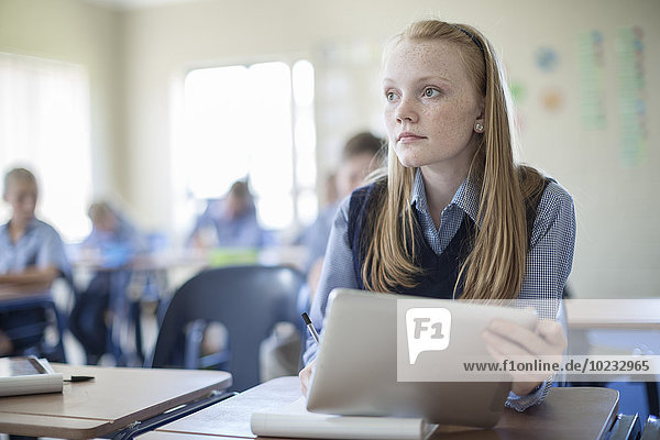 Schoolgirl in classroom with digital tablet
