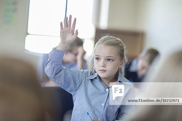 Schulmädchen im Klassenzimmer hebt die Hand