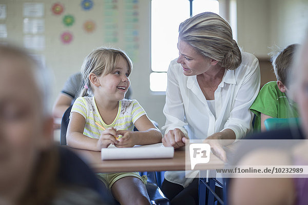 Smiling teacher and schoolgirl in classroom