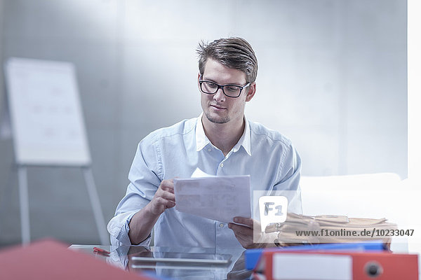 Porträt eines jungen Geschäftsmannes bei der Dokumentenprüfung am Schreibtisch