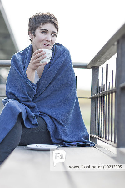 Frau mit blauer Decke trinkt Kaffee