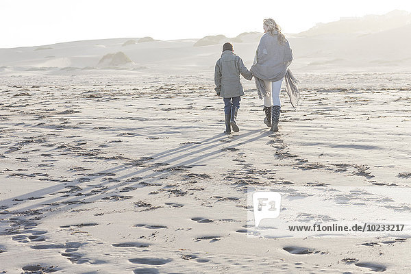 Südafrika  Kapstadt  Mutter und ihr Sohn gehen am Strand spazieren.